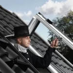 Coșar deschizând fereastra de acces VELUX GXU montată pe acoperiș cu țiglă