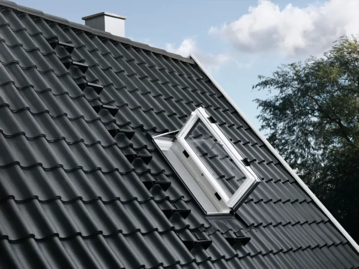 Fereastră de acces VELUX GXU deschisă pe acoperiș cu învelitoare metalică
