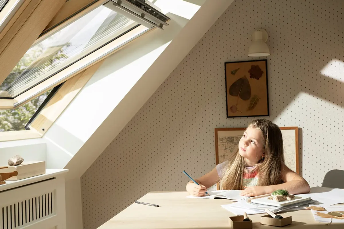 Fereastră de mansardă VELUX deschisă, lumină naturală în cameră de studiu